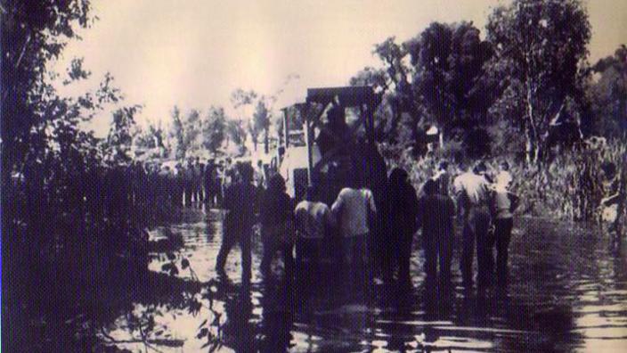 Sepia photo of people and police in lake 